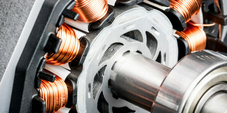 Detail of copper winding, stack and shaft of a  electric permeant magnet motor for home appliances. Selective focus and white background.