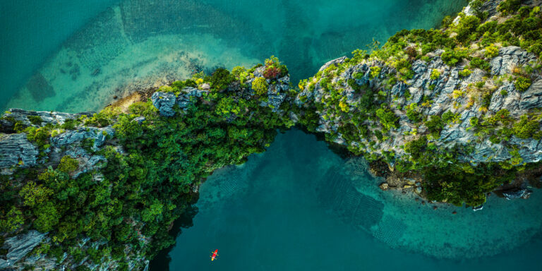 Drone view on rocks and canoes floating on turquoise water
